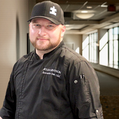 A photo of Chef Thomas Ferguson from the Paducah-McCracken Co. Convention & Expo Center Kitchen standing in the hallway of the Paducah Convention Center with his arms crossed. 